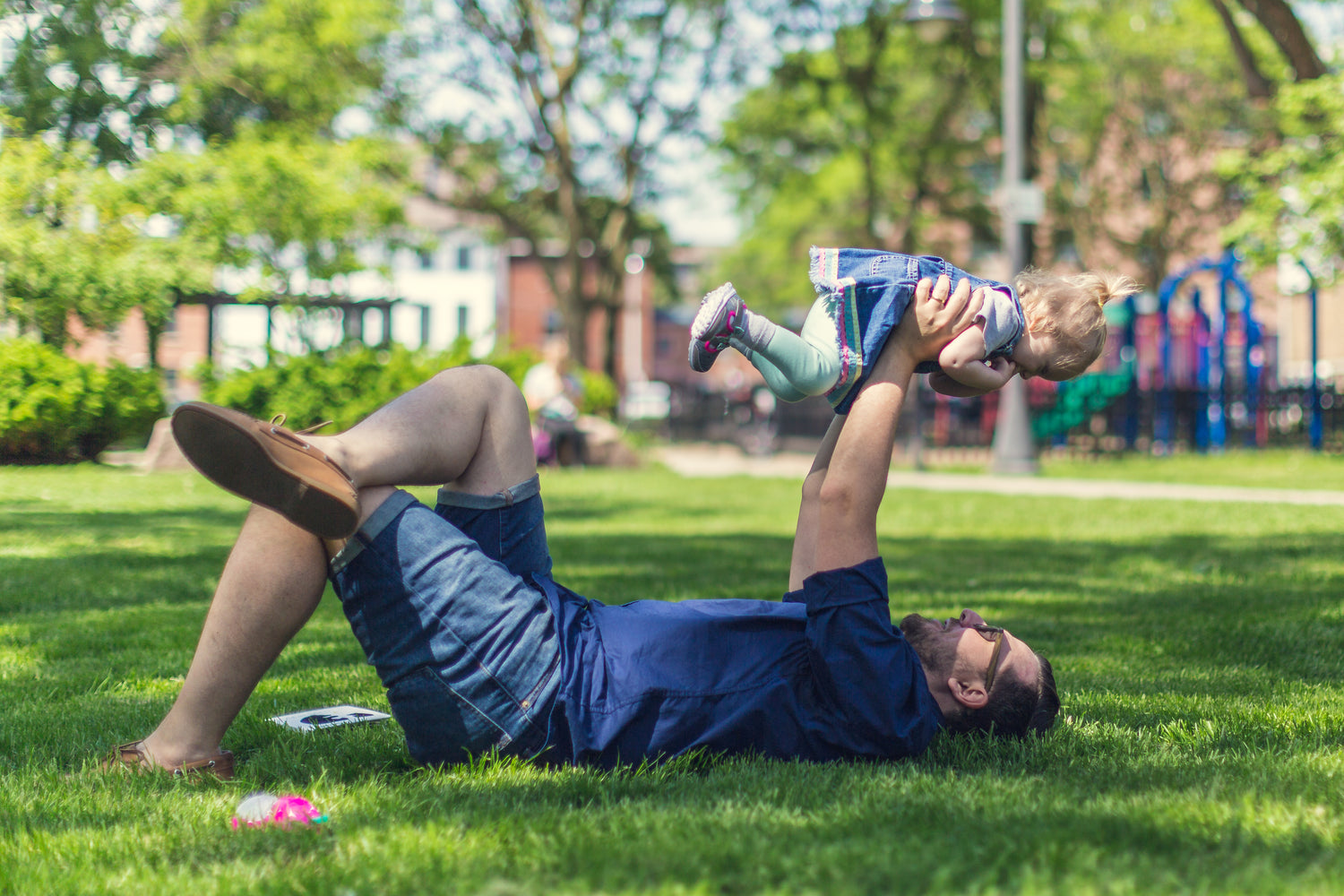 dad laying on the grass holding his daughter