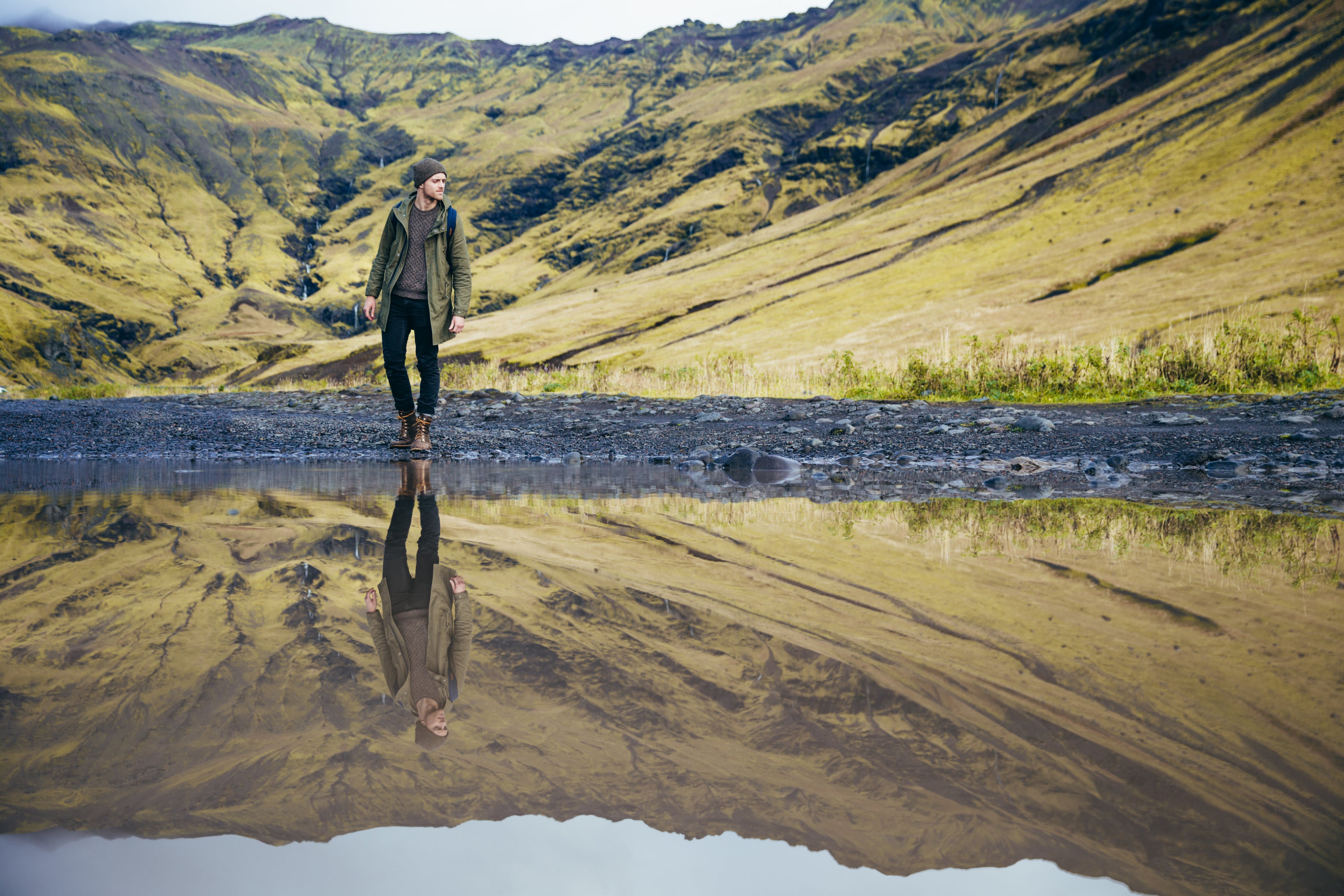 man standing at edge of lake reflection in water